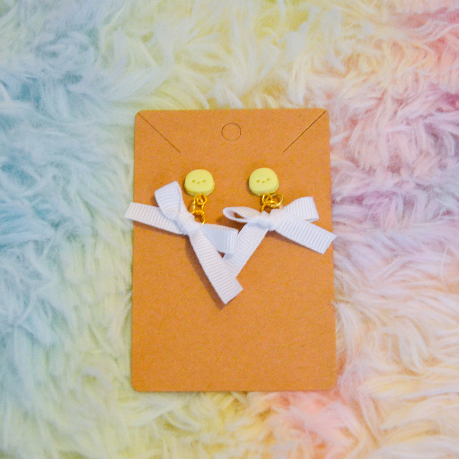 Yellow chick bow earrings against rainbow background