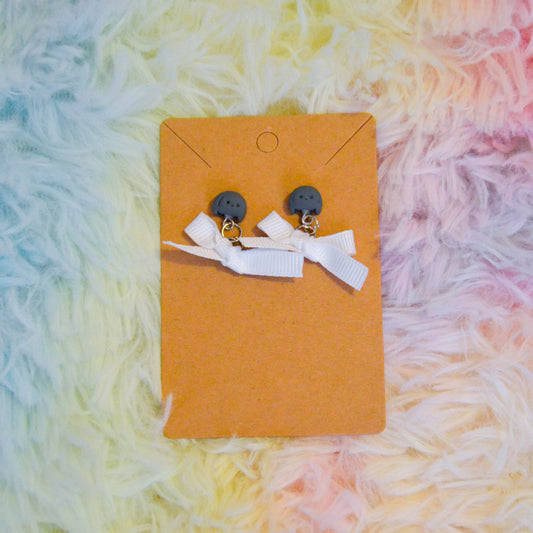 Gray bunny bow earrings against rainbow background